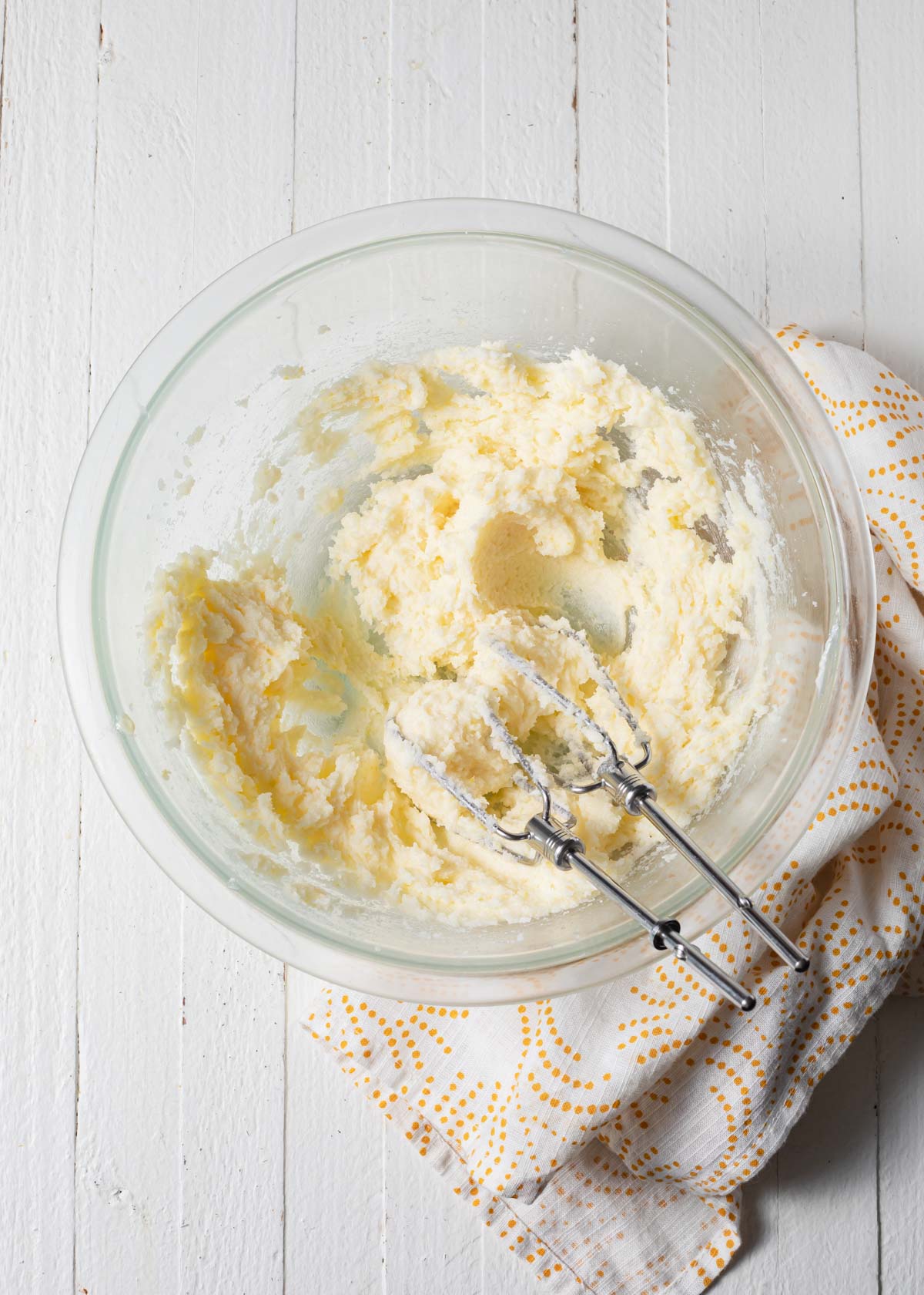 Whipped butter and sugar in a glass bowl with hand beaters