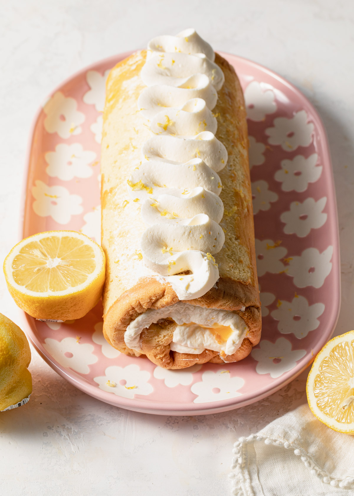 Piped whipped cream on top of a lemon roll cake
