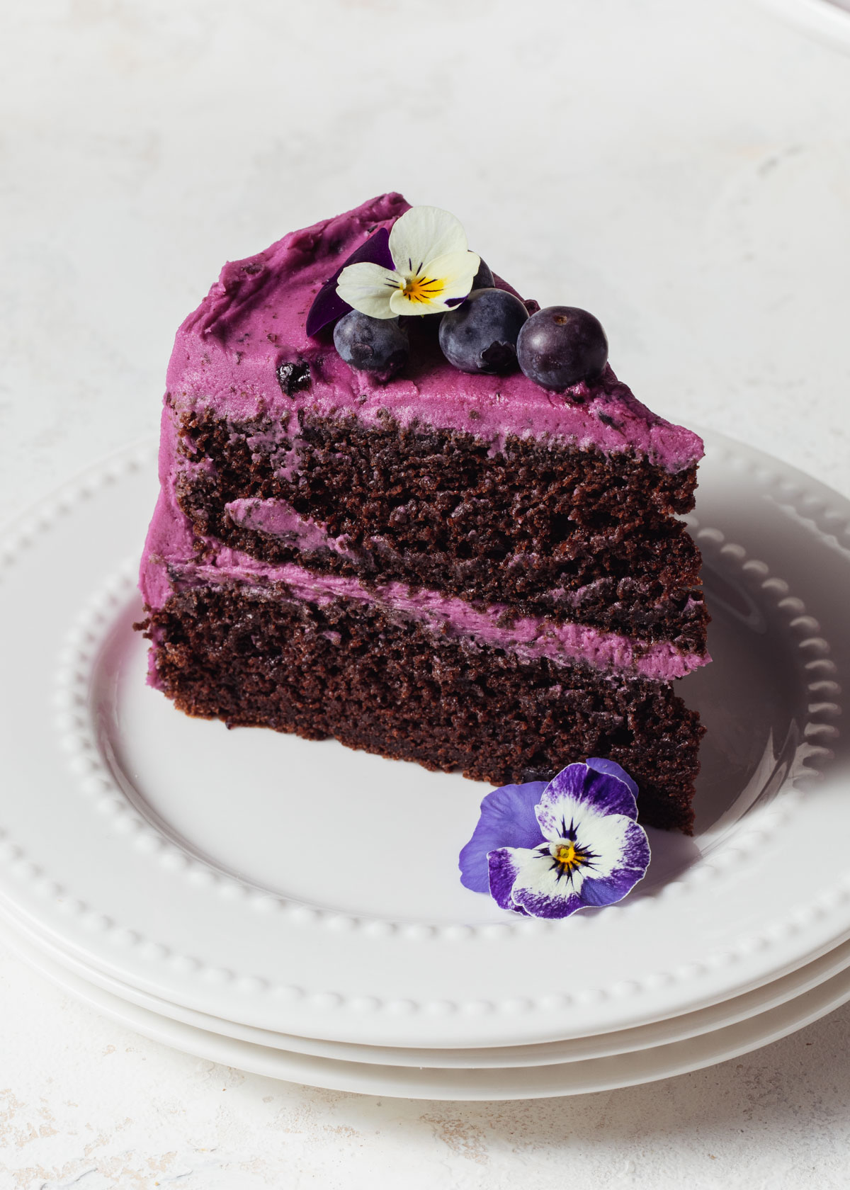 A slice of blueberry chocolate cake with fresh blueberries on top