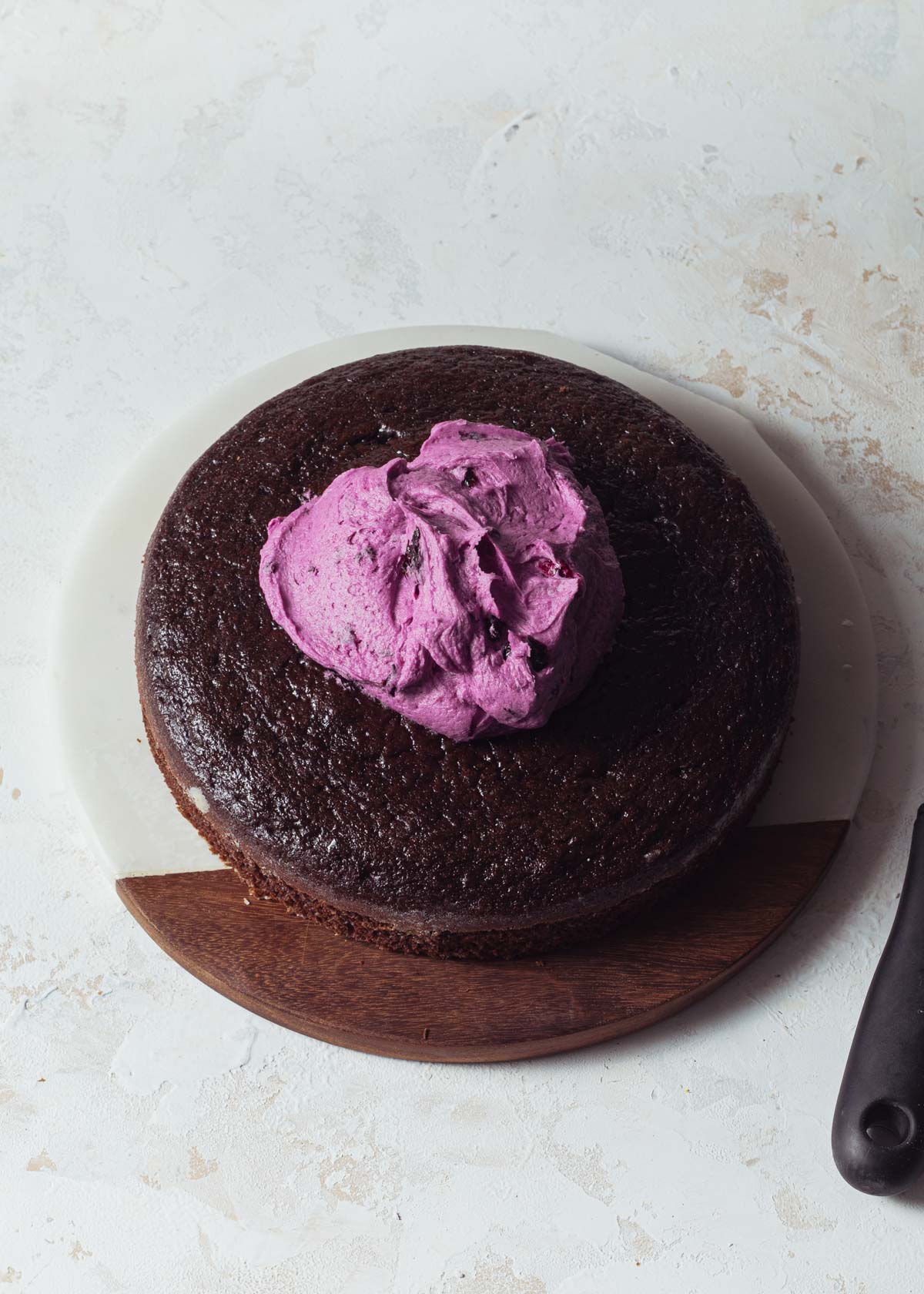 A layer of chocolate cake with blueberry frosting