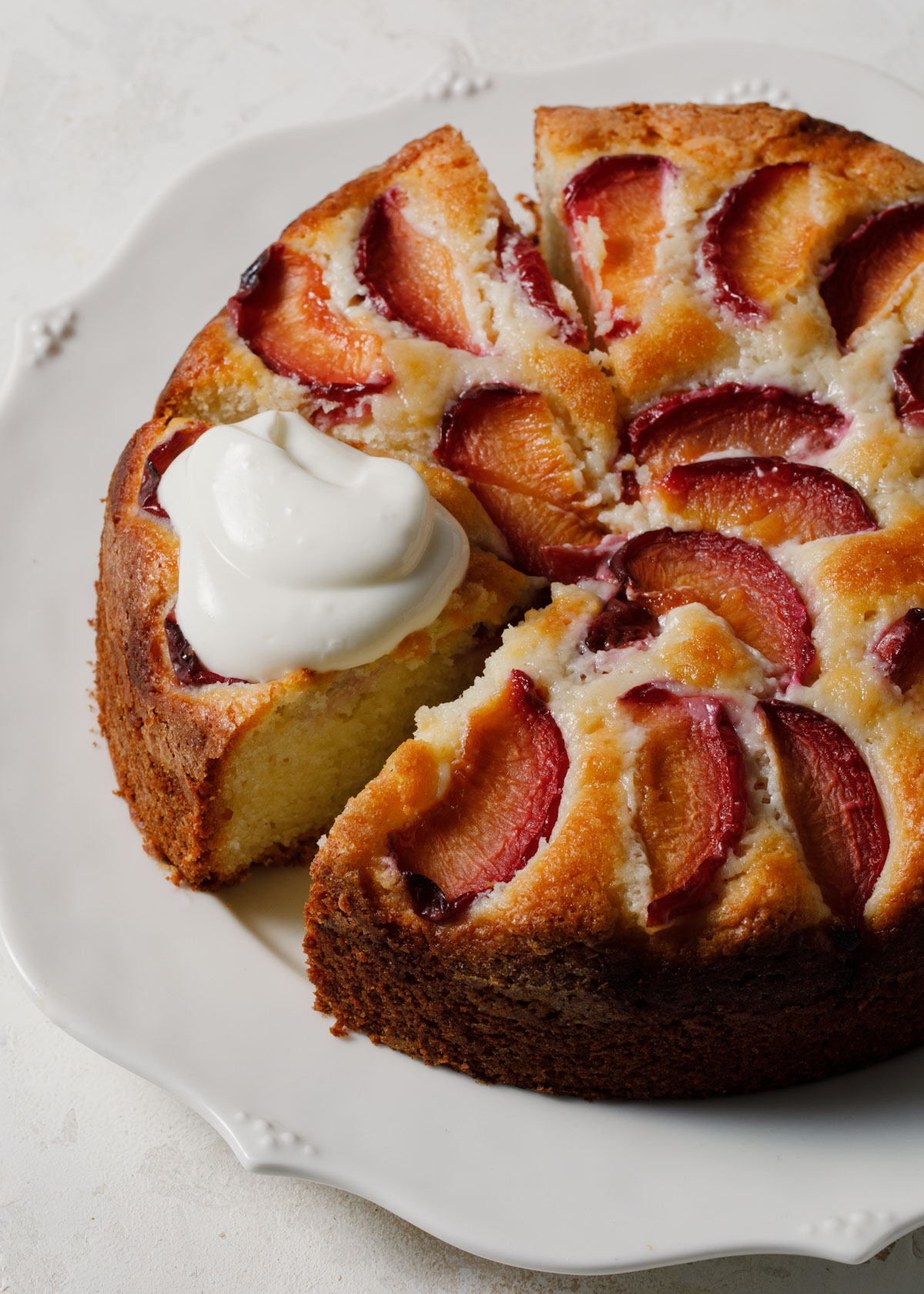 A baked plum cake with a dollop of cream on top