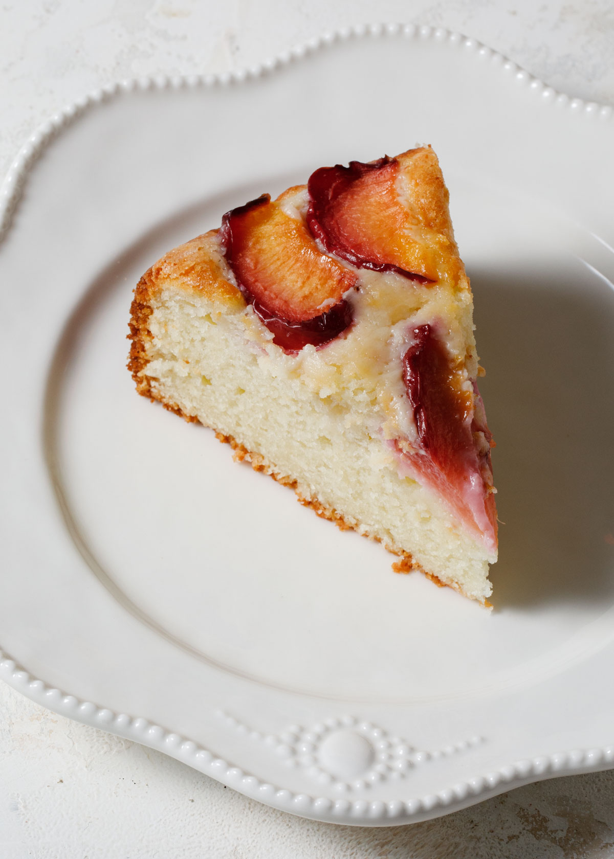 A slice of plum yogurt cake on a white plate