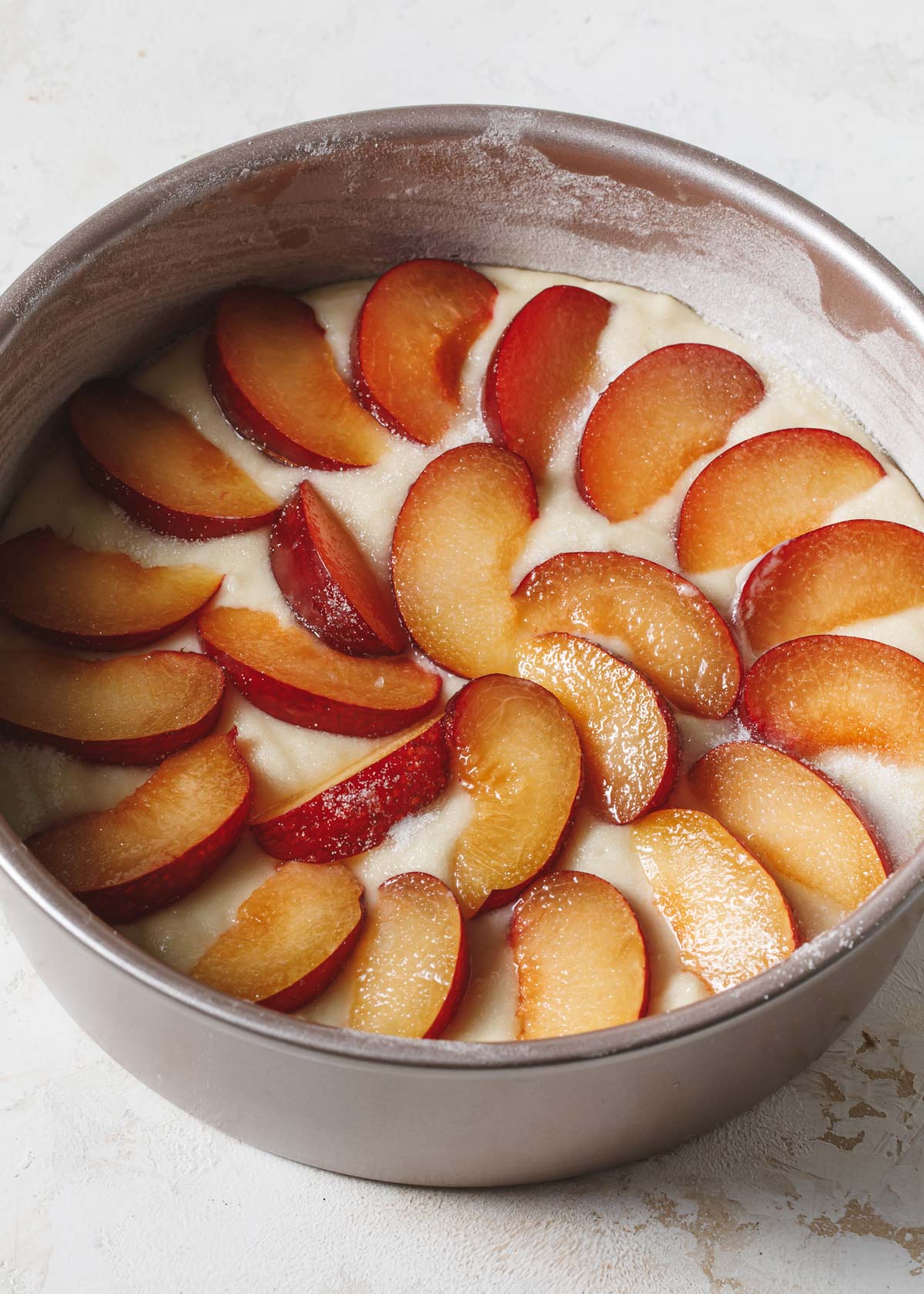 Slices of fresh plums on top of cake batter before baking