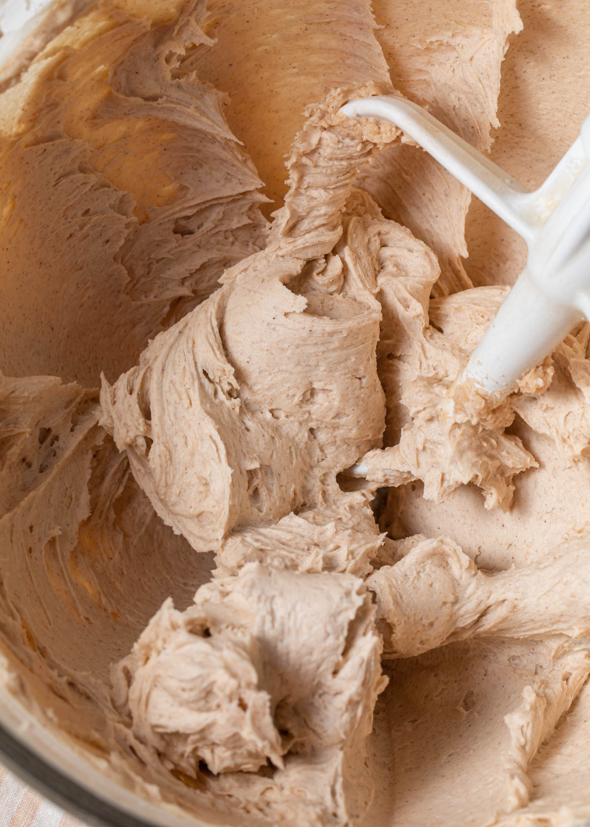 A close-up of whipped cinnamon buttercream in a mixing bowl