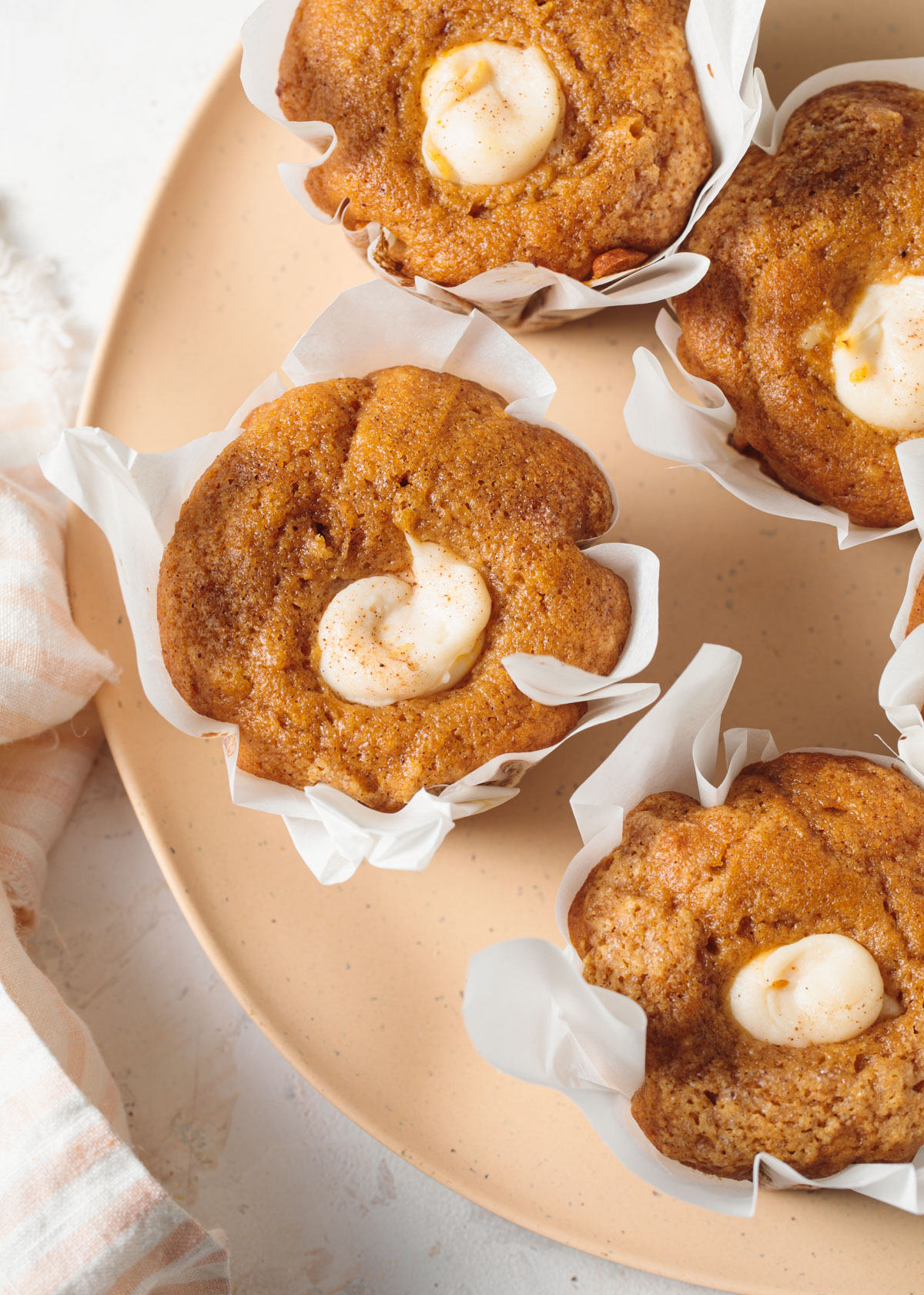 A plate of pumpkin muffins with cream cheese on top