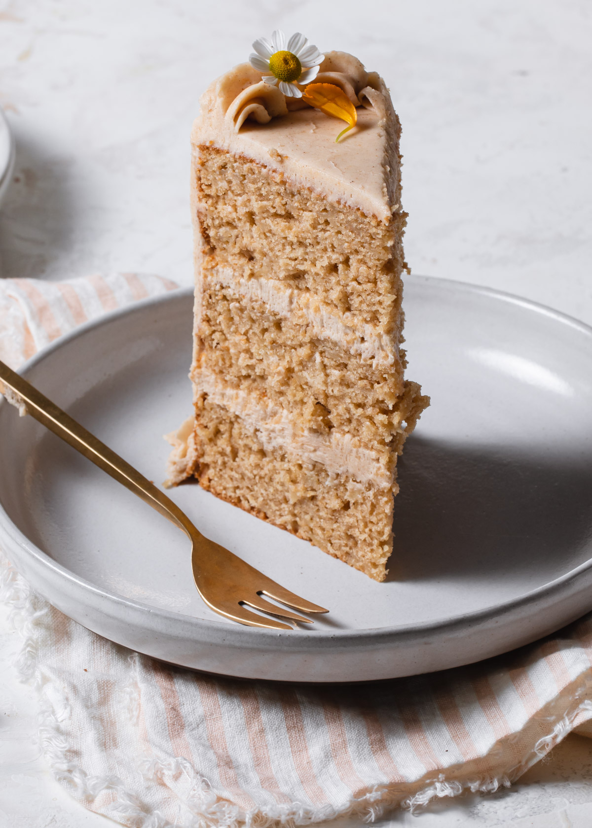 A tall slice of pumpkin cake layered with cinnamon frosting