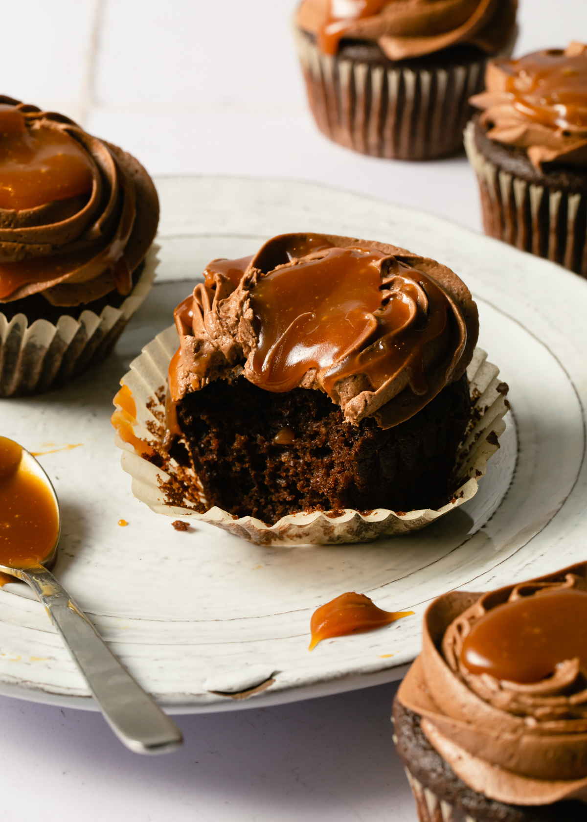 A bite out of a chocolate cupcake with drippy caramel on top