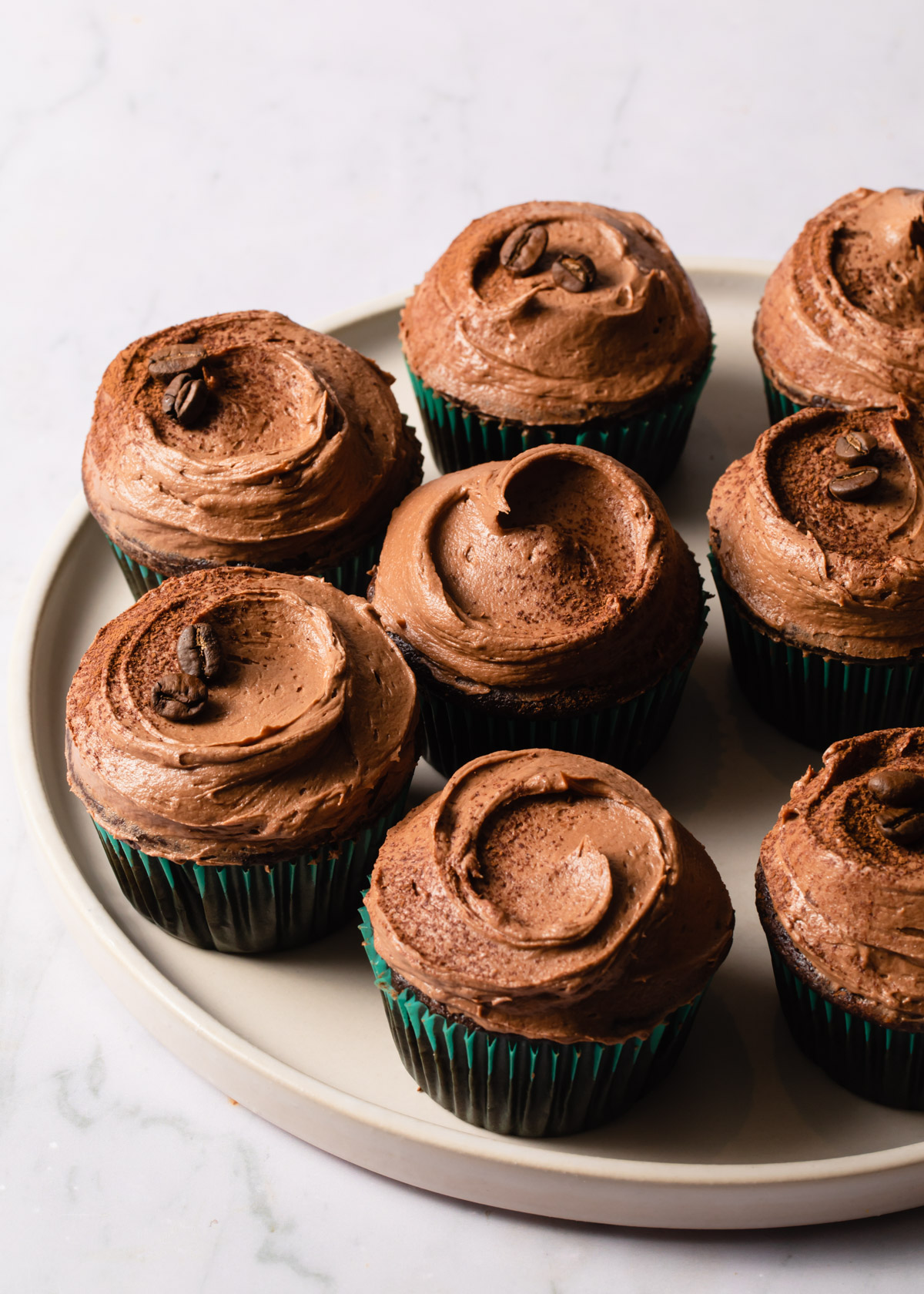 A platter of mocha cupcakes with swirls of frosting on top