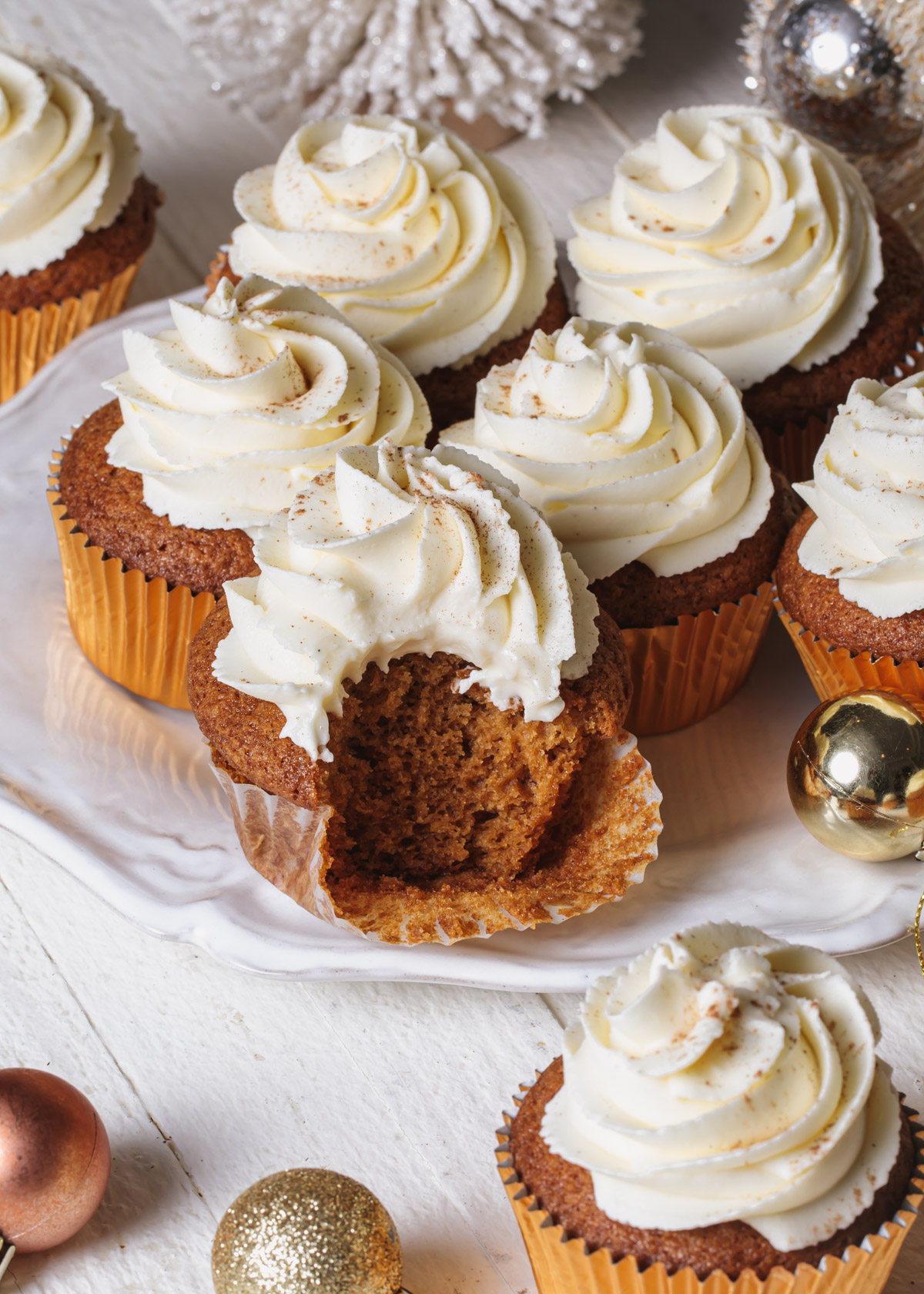 Gingerbread cupcakes with whipped white chocolate ganache frosting swirls on a white platter