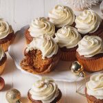 Gingerbread cupcakes with whipped white chocolate ganache frosting swirls on a white platter