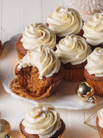 Gingerbread cupcakes with whipped white chocolate ganache frosting swirls on a white platter