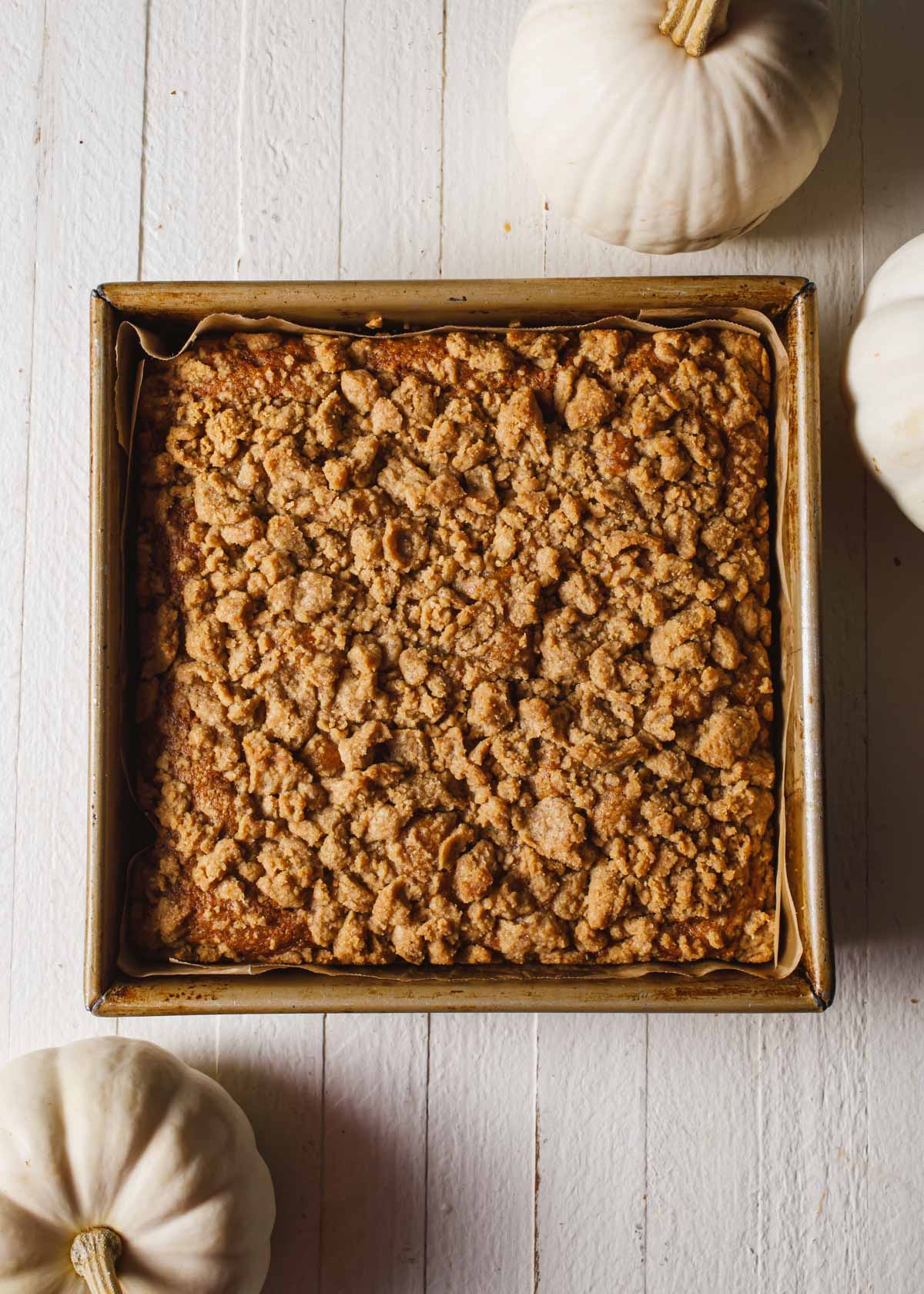 A baked pumpkin coffee cake with crumb topping in a square pan.
