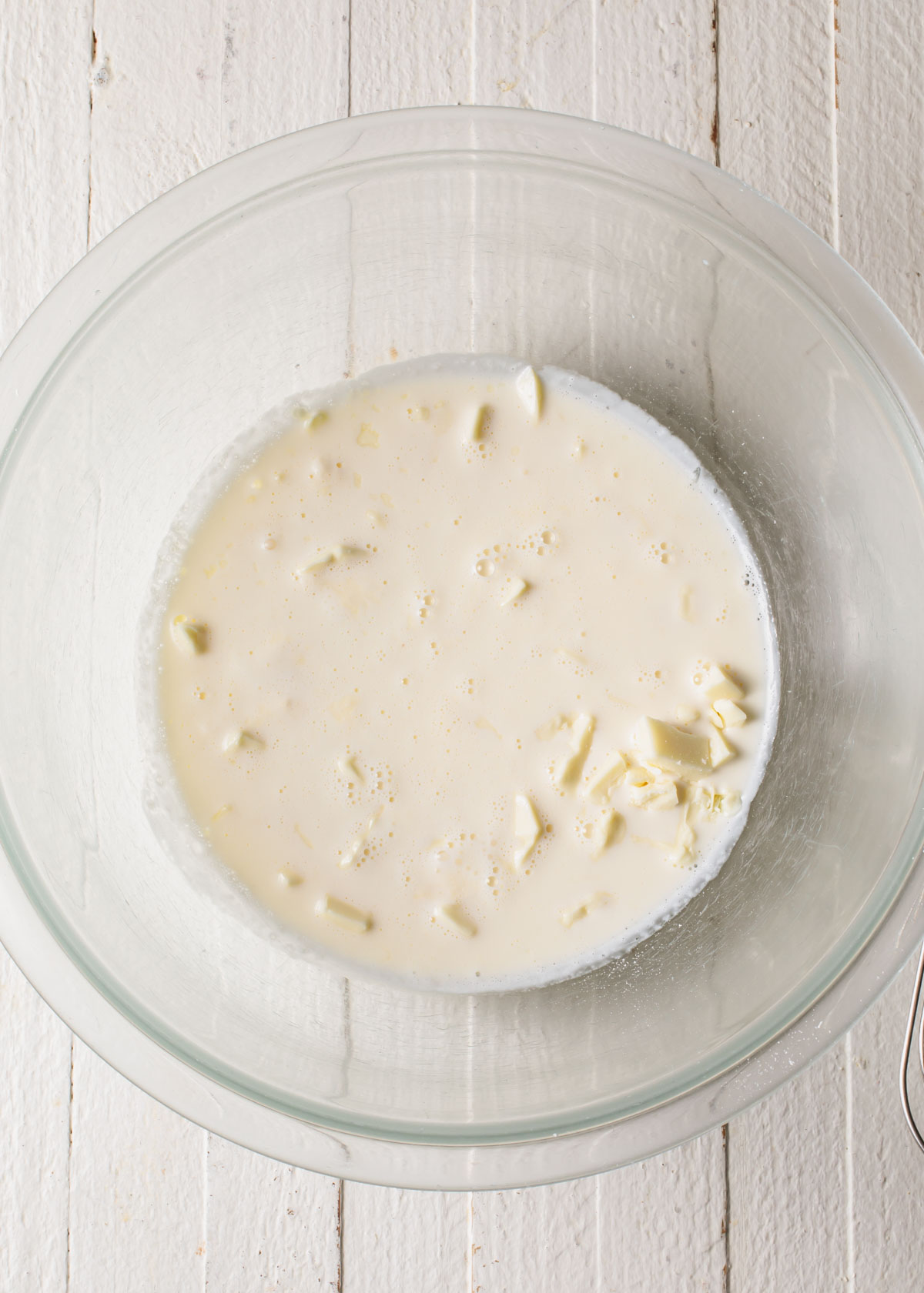 White chocolate and warm cream melting in a glass bowl