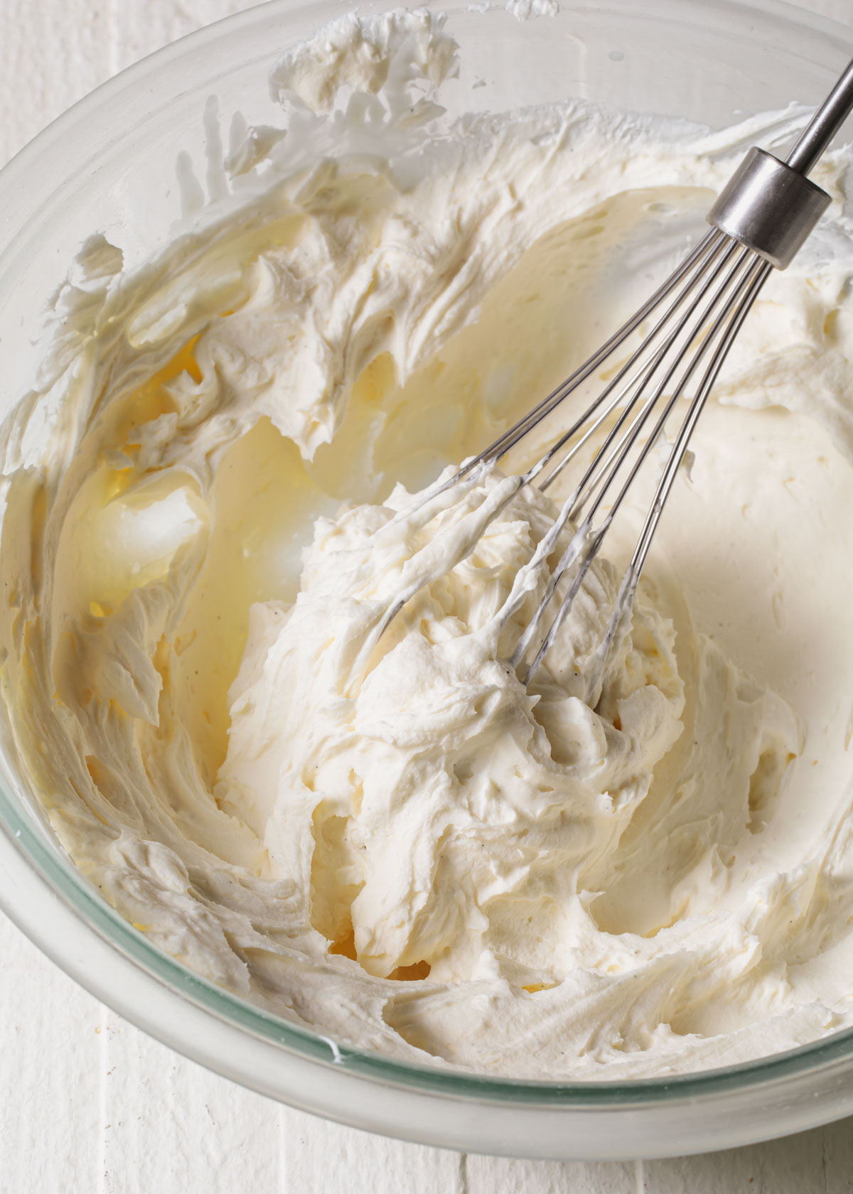 Whipped up white chocolate ganache in a bowl with a whisk