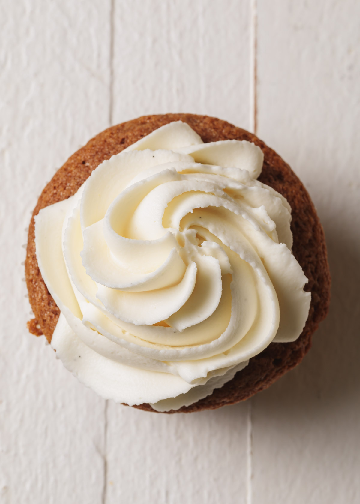 Whipped white chocolate ganache frosting swirled on top of a cupcake