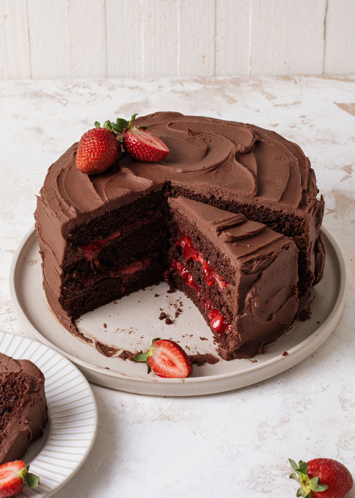 A three layer chocolate strawberry cake with fudge frosting