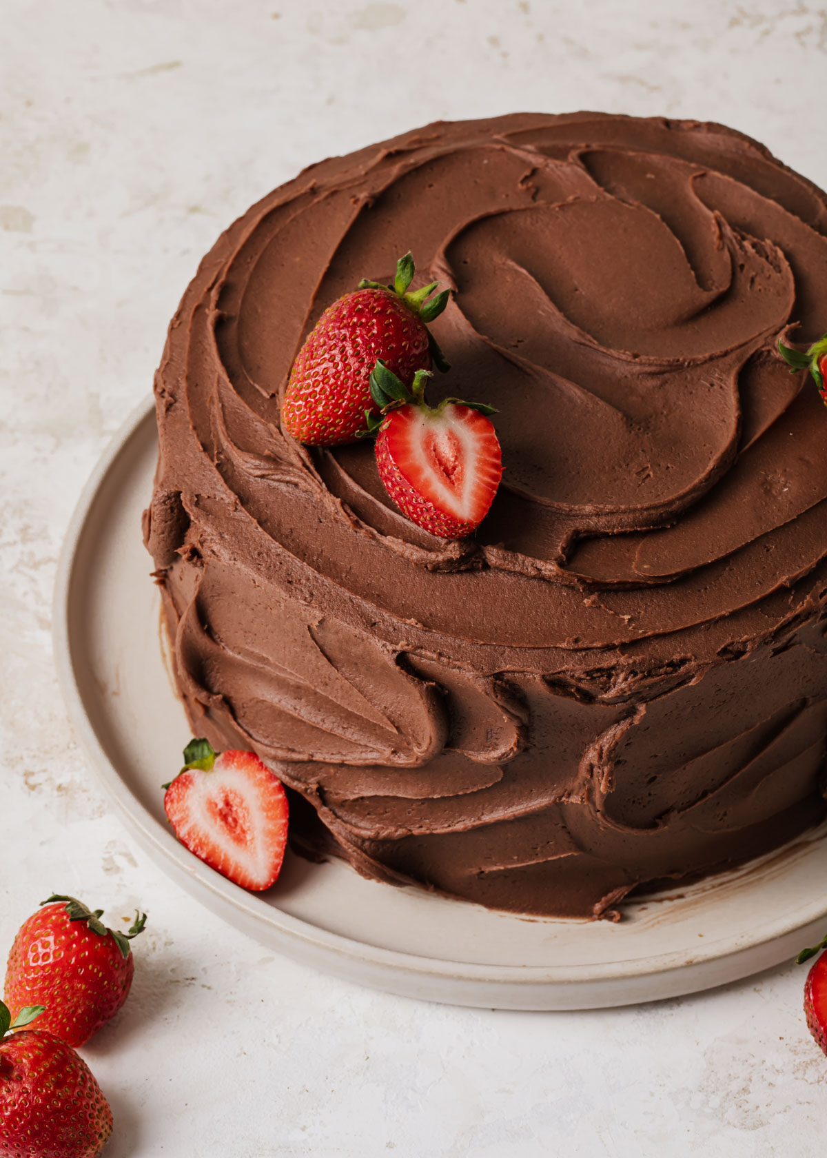 A chocolate strawberry layer cake with swirls of fudge frosting