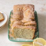 A sliced and glazed lemon poppy seed loaf cake set on a plate