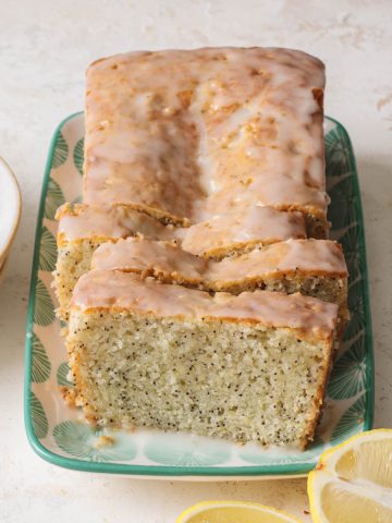 A sliced and glazed lemon poppy seed loaf cake set on a plate