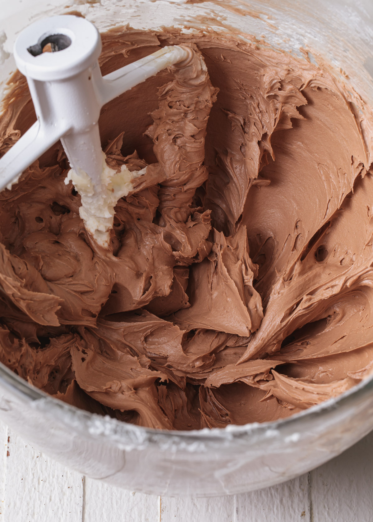 A mixing bowl with silky milk chocolate frosting inside