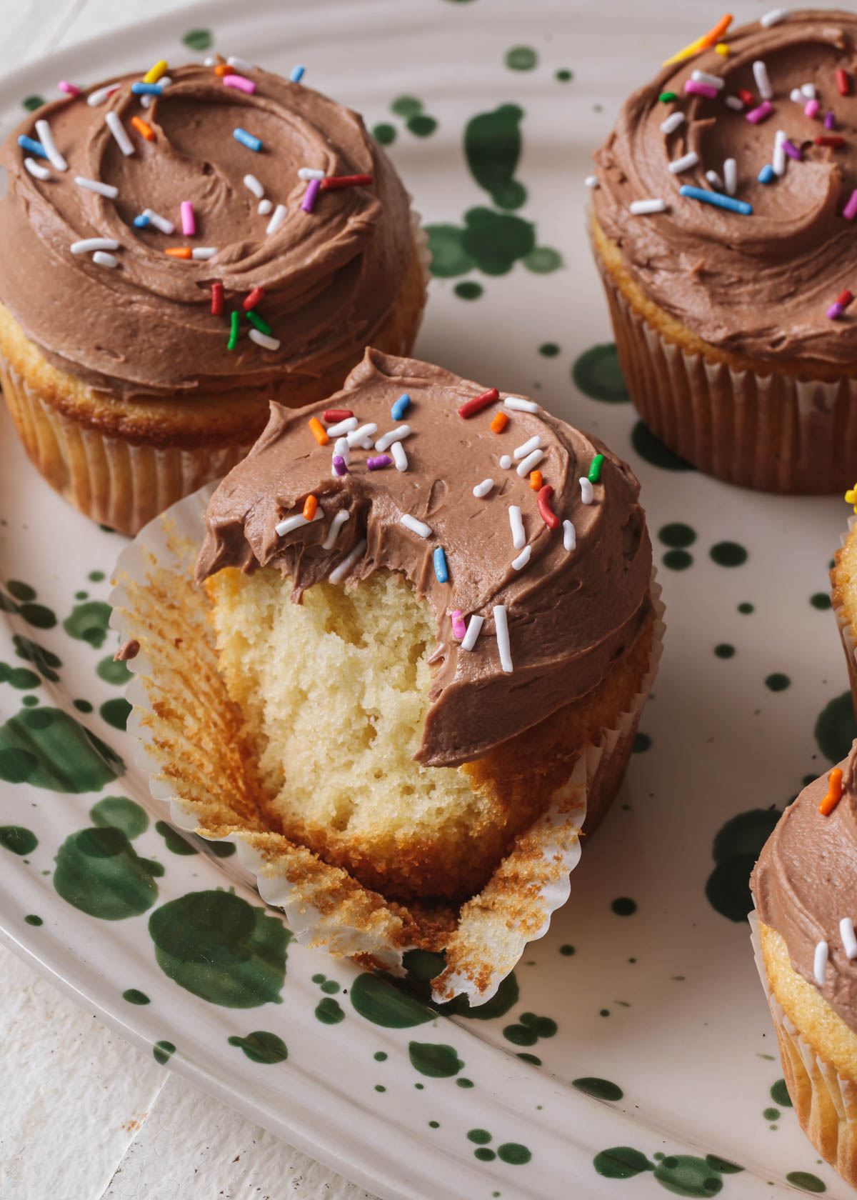 Vanilla cupcakes with milk chocolate buttercream and sprinkles on top
